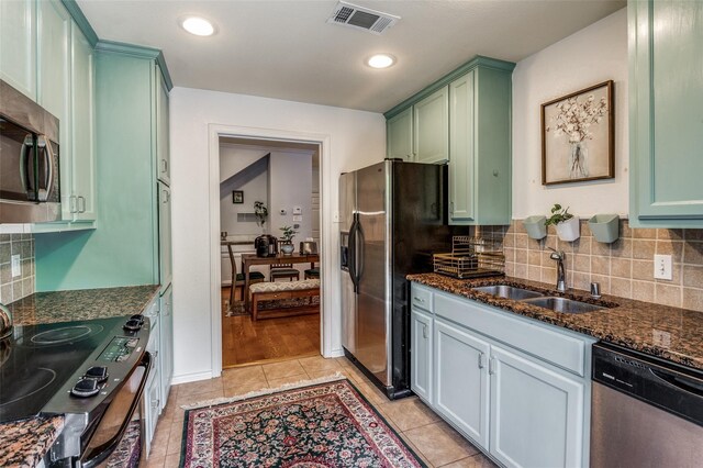 17342 Remington Park Pl, Dallas, TX 75252 - kitchen with appliances with stainless steel finishes, green cabinets, dark stone countertops, backsplash, and light tile patterned flooring