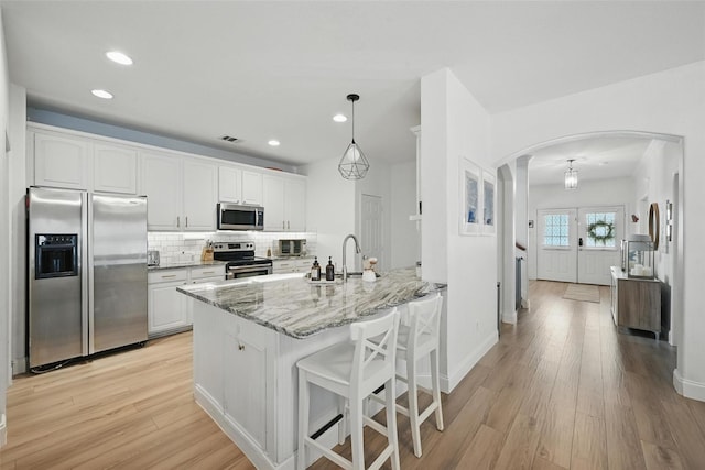 1828 Brown Thrasher Blvd, Savannah, TX 76227 - kitchen featuring stainless steel appliances, arched walkways, white cabinetry, light wood-type flooring, and a peninsula