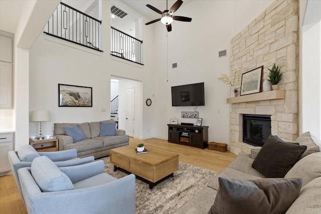 8417 Wembley, The Colony, TX 75056 - living room with light wood-type flooring, a ceiling fan, stairway, a fireplace, and a high ceiling