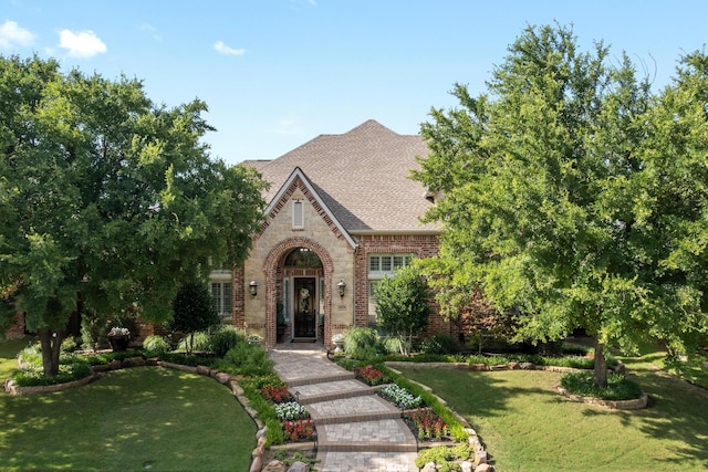 4896 Corinthian Bay Dr, Frisco, TX 75034 - tudor house with a front yard, brick siding, a shingled roof, and stone siding