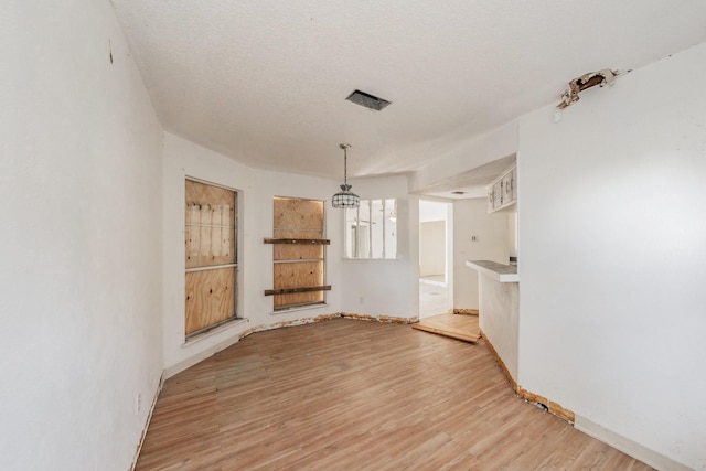 3922 Greenway Dr, Garland, TX 75041 - unfurnished dining area with light wood-style flooring, a chandelier, and a textured ceiling