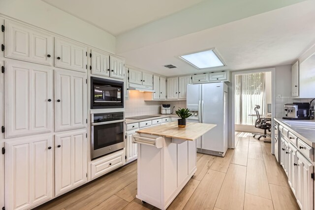 2202 Southern Ct, Carrollton, TX 75006 - kitchen featuring black appliances, tasteful backsplash, wood counters, a kitchen island, and light wood finished floors