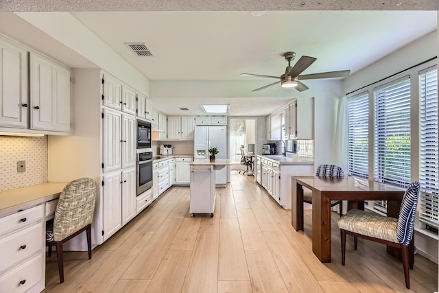 2202 Southern Ct, Carrollton, TX 75006 - kitchen with oven, refrigerator with ice dispenser, black microwave, a ceiling fan, and decorative backsplash