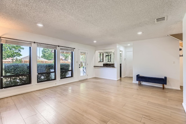2202 Southern Ct, Carrollton, TX 75006 - unfurnished living room with a textured ceiling, recessed lighting, and light wood-style flooring