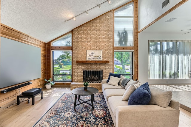 2202 Southern Ct, Carrollton, TX 75006 - living room with healthy amount of natural light, high vaulted ceiling, wooden walls, a textured ceiling, and hardwood / wood-style floors