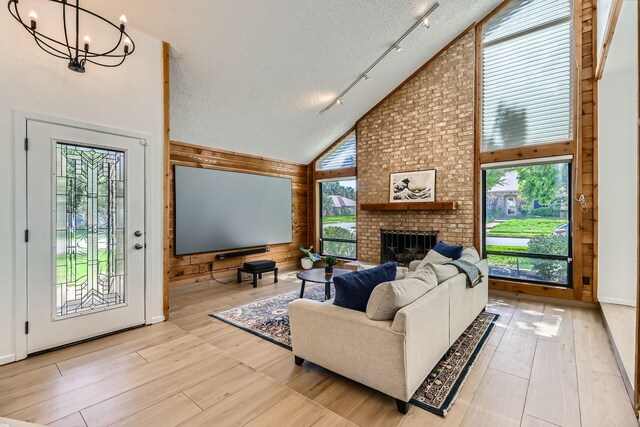 2202 Southern Ct, Carrollton, TX 75006 - living room featuring track lighting, high vaulted ceiling, a textured ceiling, a chandelier, and a fireplace