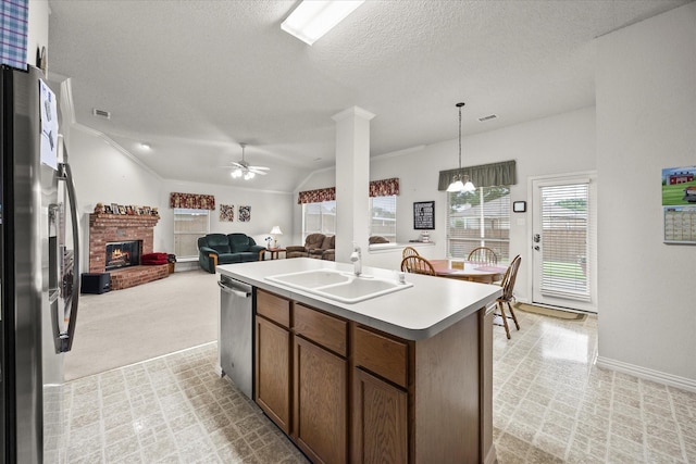 2918 Beau Dr, Mesquite, TX 75181 - kitchen featuring stainless steel appliances, a fireplace, ceiling fan, a kitchen island with sink, and lofted ceiling