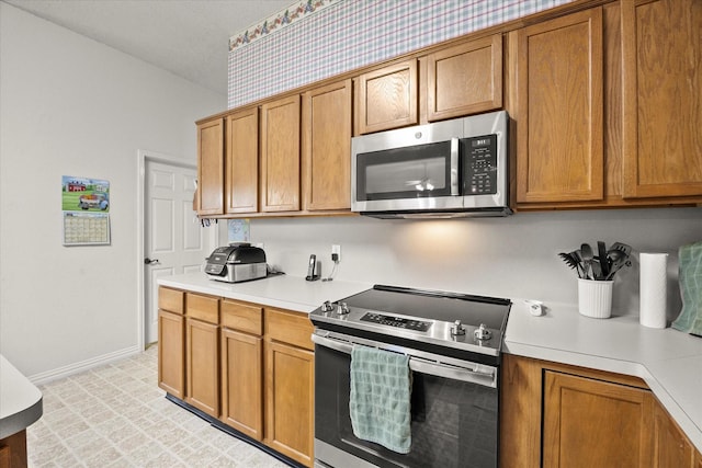 2918 Beau Dr, Mesquite, TX 75181 - kitchen featuring stainless steel appliances, brown cabinetry, and light countertops