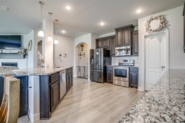 433 Joseph Ln, Crowley, TX 76036 - kitchen featuring stainless steel appliances, arched walkways, dark brown cabinetry, backsplash, and light wood-style flooring