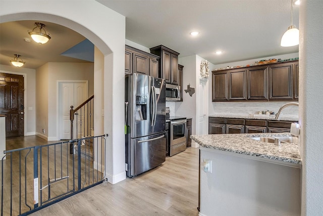 433 Joseph Ln, Crowley, TX 76036 - kitchen with appliances with stainless steel finishes, dark brown cabinets, arched walkways, light wood finished floors, and light stone countertops