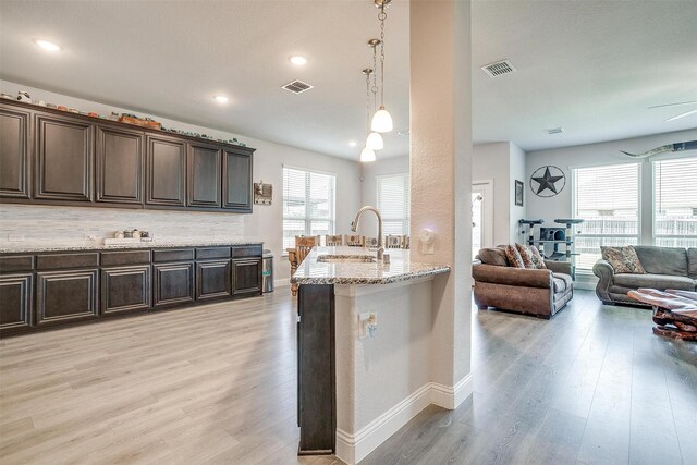 433 Joseph Ln, Crowley, TX 76036 - kitchen featuring light wood finished floors, dark brown cabinets, light stone counters, open floor plan, and decorative light fixtures