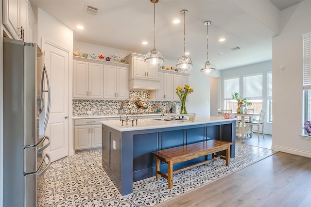 5729 Violet Crown Pl, Fort Worth, TX 76126 - kitchen featuring freestanding refrigerator, light countertops, tasteful backsplash, a kitchen island with sink, and a kitchen breakfast bar