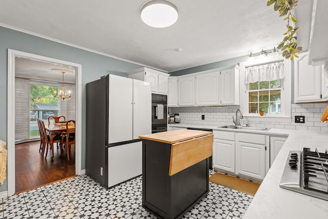 425 W Belden St, Sherman, TX 75092 - kitchen featuring freestanding refrigerator, stainless steel gas stovetop, black oven, light flooring, and ornamental molding
