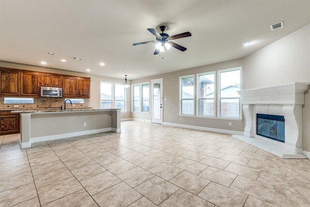 302 Shire Ln, Celina, TX 75009 - kitchen with stainless steel microwave, open floor plan, tasteful backsplash, light tile patterned floors, and a ceiling fan