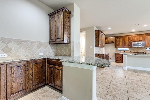 302 Shire Ln, Celina, TX 75009 - kitchen featuring stainless steel microwave, tasteful backsplash, light stone counters, recessed lighting, and light tile patterned floors