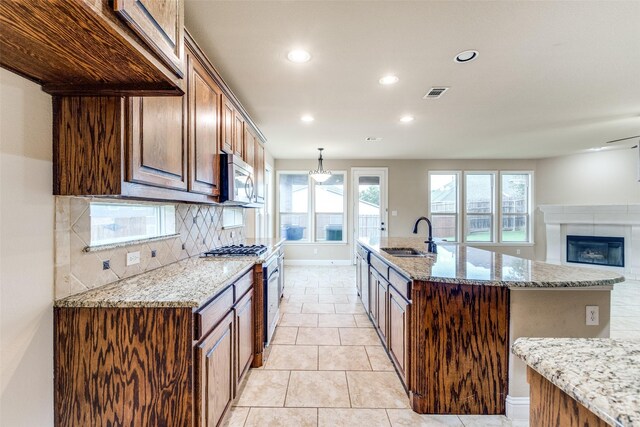 302 Shire Ln, Celina, TX 75009 - kitchen with recessed lighting, backsplash, appliances with stainless steel finishes, light stone counters, and a glass covered fireplace