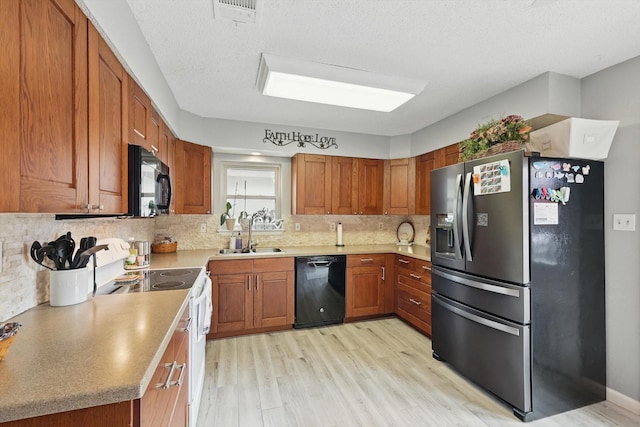 4109 Malone Ave, The Colony, TX 75056 - kitchen with black appliances, light wood-style flooring, brown cabinetry, backsplash, and light countertops