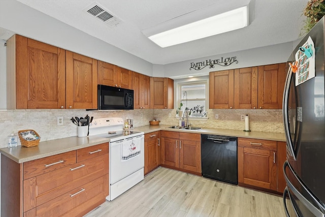 4109 Malone Ave, The Colony, TX 75056 - kitchen featuring black appliances, light wood-style flooring, brown cabinets, and tasteful backsplash