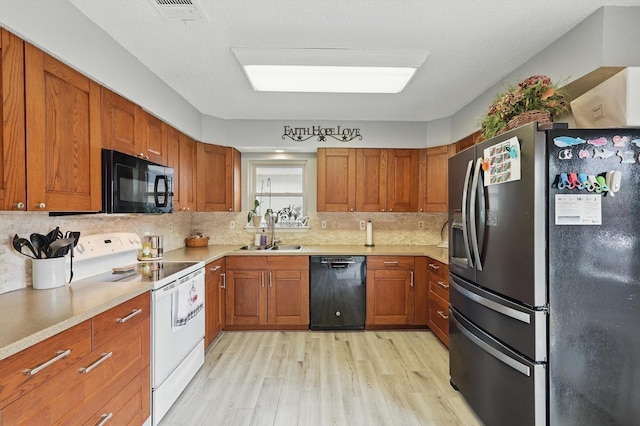 4109 Malone Ave, The Colony, TX 75056 - kitchen with black appliances, light wood finished floors, brown cabinetry, light countertops, and backsplash