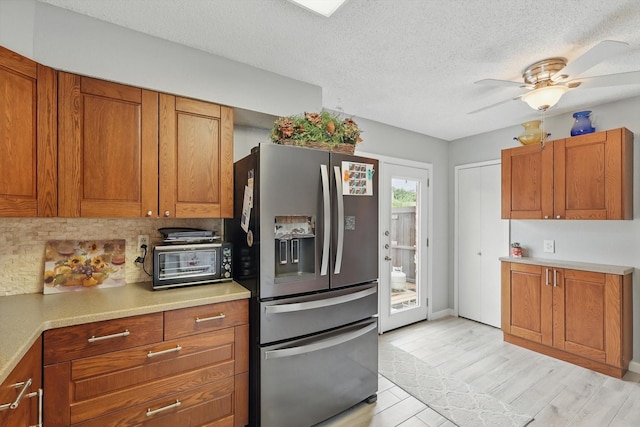 4109 Malone Ave, The Colony, TX 75056 - kitchen with stainless steel fridge, brown cabinetry, light countertops, a ceiling fan, and a textured ceiling