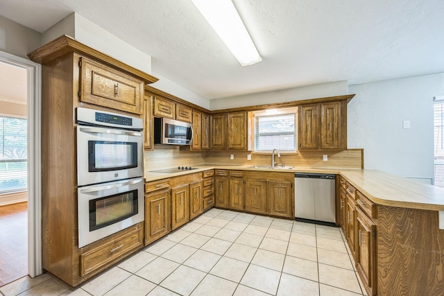 2413 Golden Willow Ln, Richardson, TX 75082 - kitchen featuring stainless steel appliances, a peninsula, light countertops, and plenty of natural light