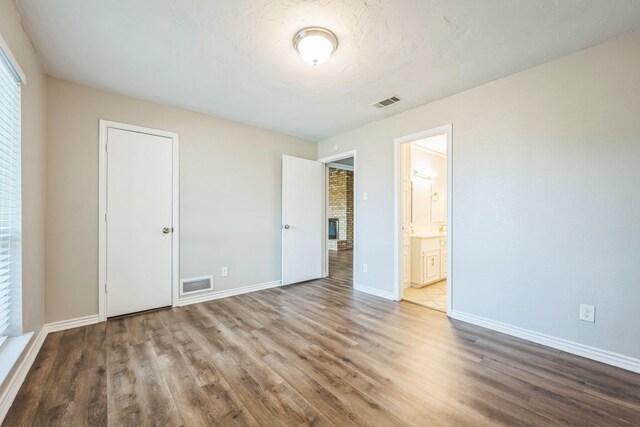 2413 Golden Willow Ln, Richardson, TX 75082 - unfurnished bedroom featuring wood finished floors, ensuite bath, and a fireplace
