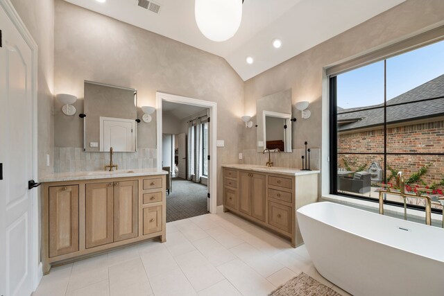 801 Cliffmoor Dr, Keller, TX 76248 - bathroom featuring lofted ceiling, two vanities, a soaking tub, tile patterned flooring, and decorative backsplash