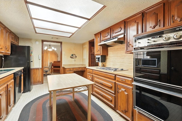 1419 Juniper Ln, Lewisville, TX 75077 - kitchen with under cabinet range hood, black appliances, a chandelier, light countertops, and wainscoting