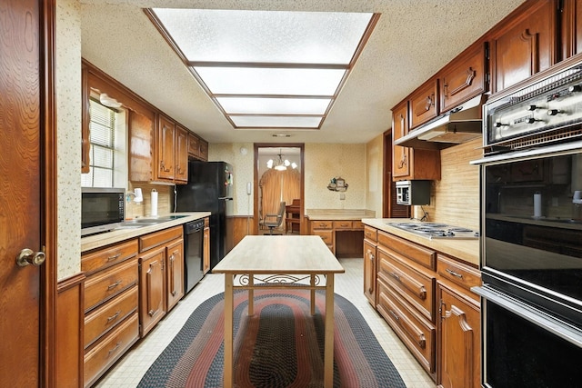 1419 Juniper Ln, Lewisville, TX 75077 - kitchen featuring black appliances, light countertops, a textured ceiling, wainscoting, and a chandelier