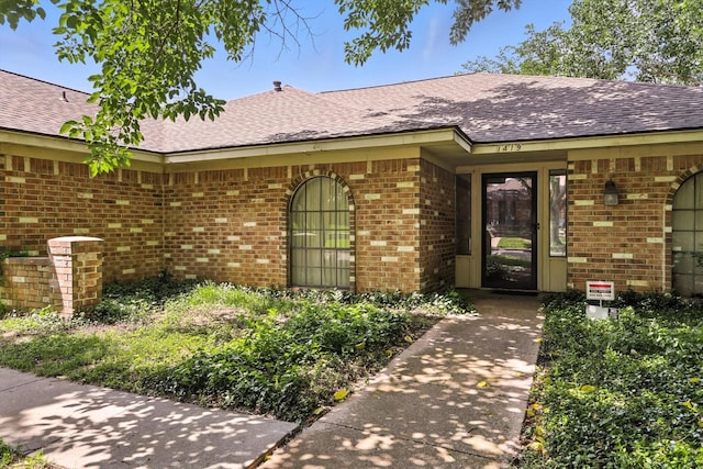 1419 Juniper Ln, Lewisville, TX 75077 - view of exterior entry featuring brick siding and a shingled roof