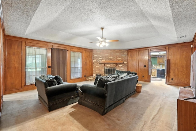 1419 Juniper Ln, Lewisville, TX 75077 - living area with ceiling fan, light carpet, a tray ceiling, wooden walls, and a fireplace