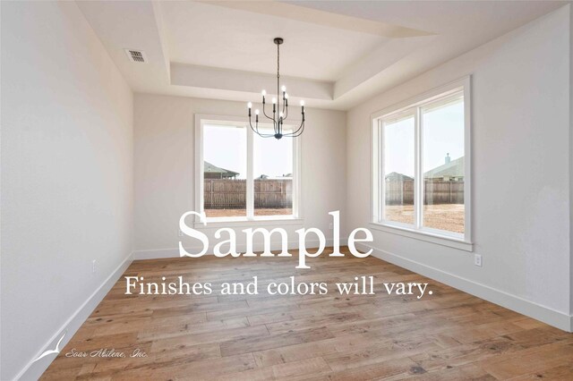 6602 Beals Creek Dr, Abilene, TX 79606 - empty room featuring a tray ceiling, a chandelier, and wood finished floors