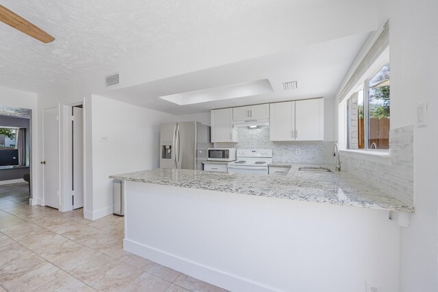22 W Townhouse Ln Unit 34, Grand Prairie, TX 75052 - kitchen with white appliances, a peninsula, light stone counters, white cabinetry, and under cabinet range hood