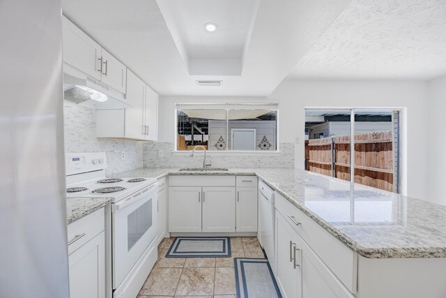 22 W Townhouse Ln Unit 34, Grand Prairie, TX 75052 - kitchen with white appliances, under cabinet range hood, decorative backsplash, a peninsula, and white cabinets