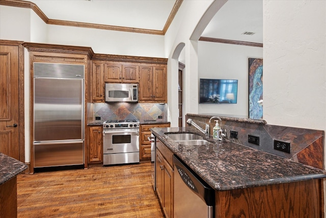 17227 Lechlade Ln, Dallas, TX 75252 - kitchen featuring high end appliances, arched walkways, backsplash, wood finished floors, and dark stone counters