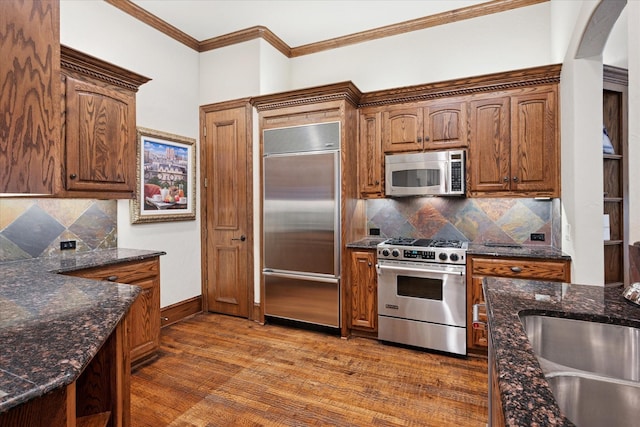 17227 Lechlade Ln, Dallas, TX 75252 - kitchen featuring high end appliances, decorative backsplash, wood finished floors, arched walkways, and dark stone counters