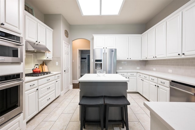 2413 Bachman Dr, Flower Mound, TX 75028 - kitchen featuring stainless steel appliances, under cabinet range hood, backsplash, and white cabinetry
