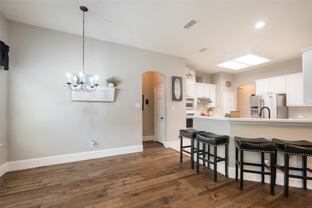 2413 Bachman Dr, Flower Mound, TX 75028 - kitchen with stainless steel appliances, arched walkways, a breakfast bar area, and dark wood-type flooring
