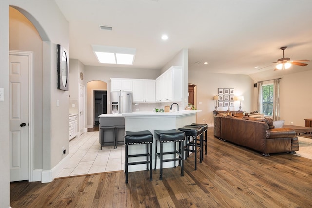 2413 Bachman Dr, Flower Mound, TX 75028 - kitchen with stainless steel refrigerator with ice dispenser, open floor plan, arched walkways, a peninsula, and light wood finished floors