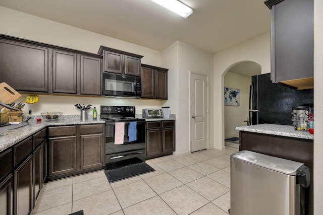 5921 Obsidian Creek Dr, Fort Worth, TX 76179 - kitchen with black appliances, arched walkways, dark brown cabinetry, light tile patterned floors, and light stone countertops