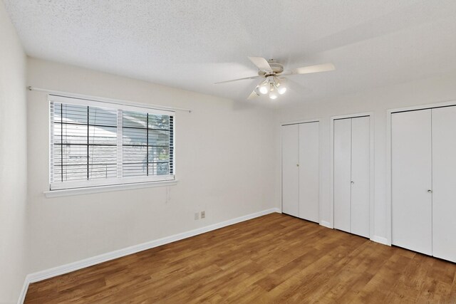 1225 Briarcove Dr, Richardson, TX 75081 - unfurnished bedroom featuring wood finished floors, multiple closets, ceiling fan, and a textured ceiling