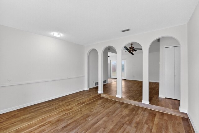 1225 Briarcove Dr, Richardson, TX 75081 - empty room featuring a ceiling fan, wood finished floors, and arched walkways