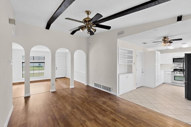 1225 Briarcove Dr, Richardson, TX 75081 - unfurnished living room with a ceiling fan, arched walkways, beam ceiling, and light wood-type flooring