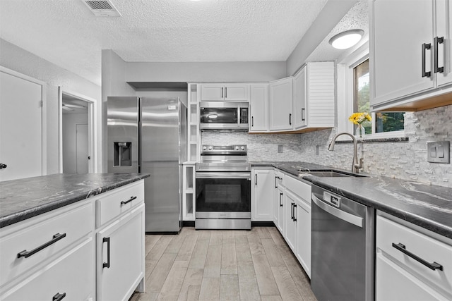 202 Lee Ln, Lorena, TX 76655 - kitchen with appliances with stainless steel finishes, light wood-type flooring, a textured ceiling, white cabinetry, and decorative backsplash