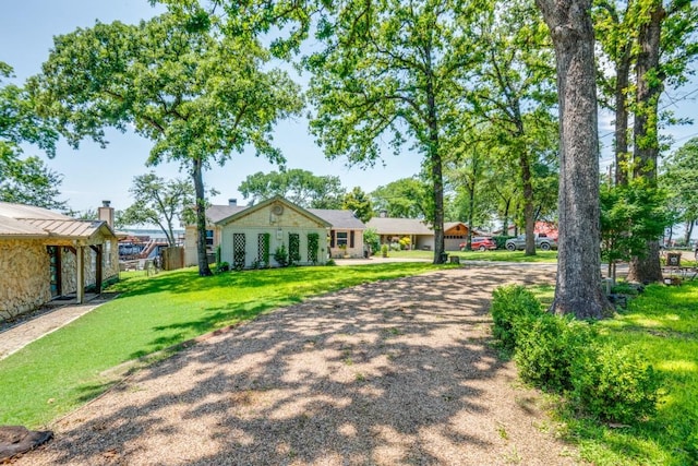 105 Causeway Ct, Gun Barrel City, TX 75156 - view of front of home featuring stone siding, a chimney, a front lawn, and driveway
