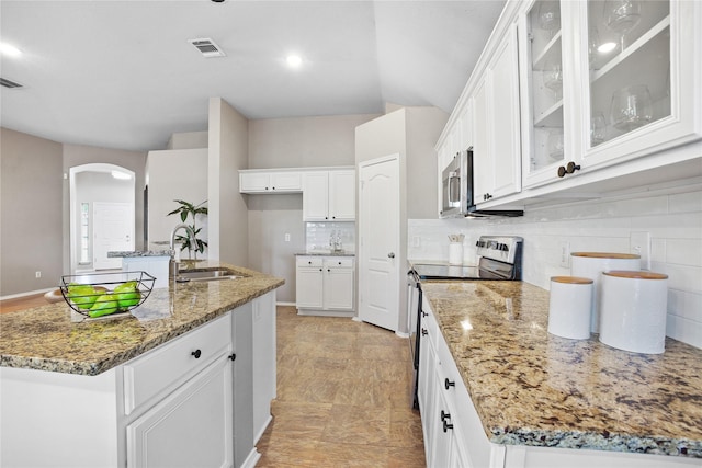 733 Atascosa Ave, Fort Worth, TX 76120 - kitchen featuring appliances with stainless steel finishes, light stone counters, tasteful backsplash, arched walkways, and white cabinetry