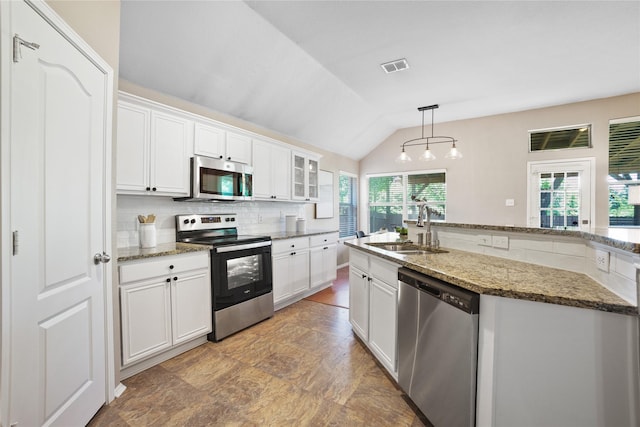 733 Atascosa Ave, Fort Worth, TX 76120 - kitchen featuring appliances with stainless steel finishes, backsplash, white cabinets, vaulted ceiling, and pendant lighting