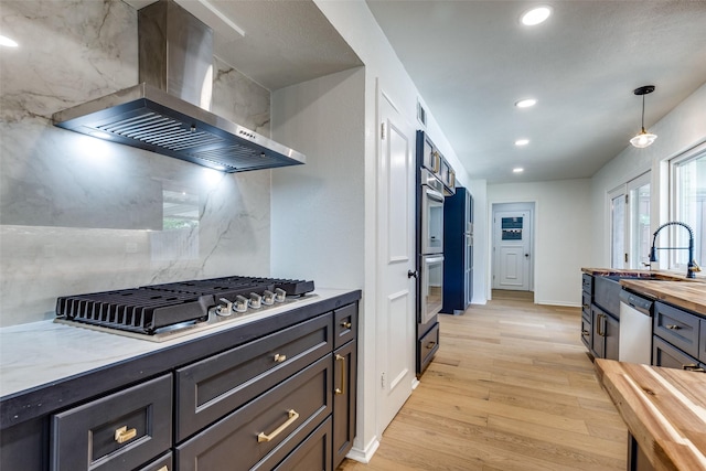 2955 Las Campanas Dr, Farmers Branch, TX 75234 - kitchen with wall chimney range hood, wood counters, appliances with stainless steel finishes, light wood finished floors, and recessed lighting