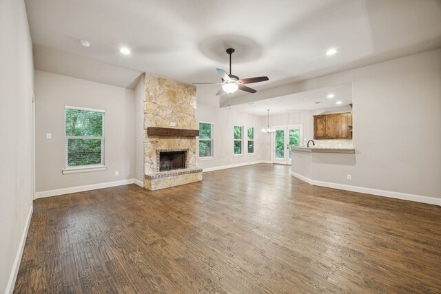 149 Ty Ln, Azle, TX 76020 - unfurnished living room featuring a ceiling fan, a stone fireplace, vaulted ceiling, dark wood-style flooring, and a chandelier