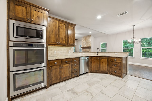149 Ty Ln, Azle, TX 76020 - kitchen featuring appliances with stainless steel finishes, a peninsula, backsplash, light stone countertops, and recessed lighting